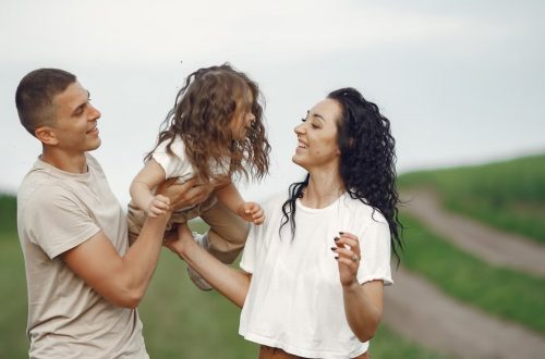 A joyful family moment outdoors with parents playing with their daughter.