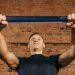 Man performing workout with resistance band against a brick wall backdrop.